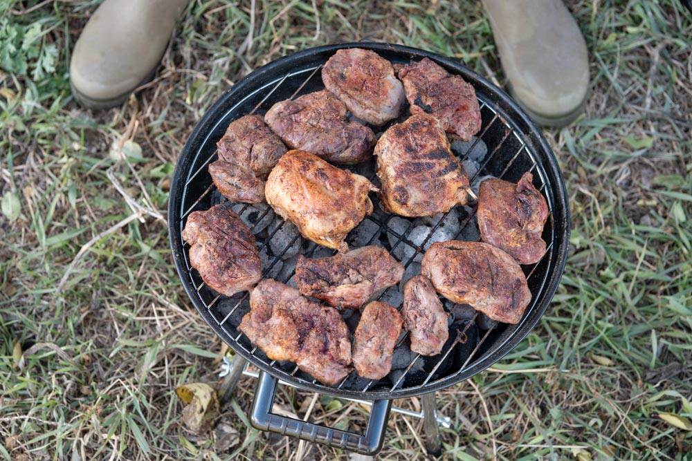 duck breasts grilling over a charcoal fire