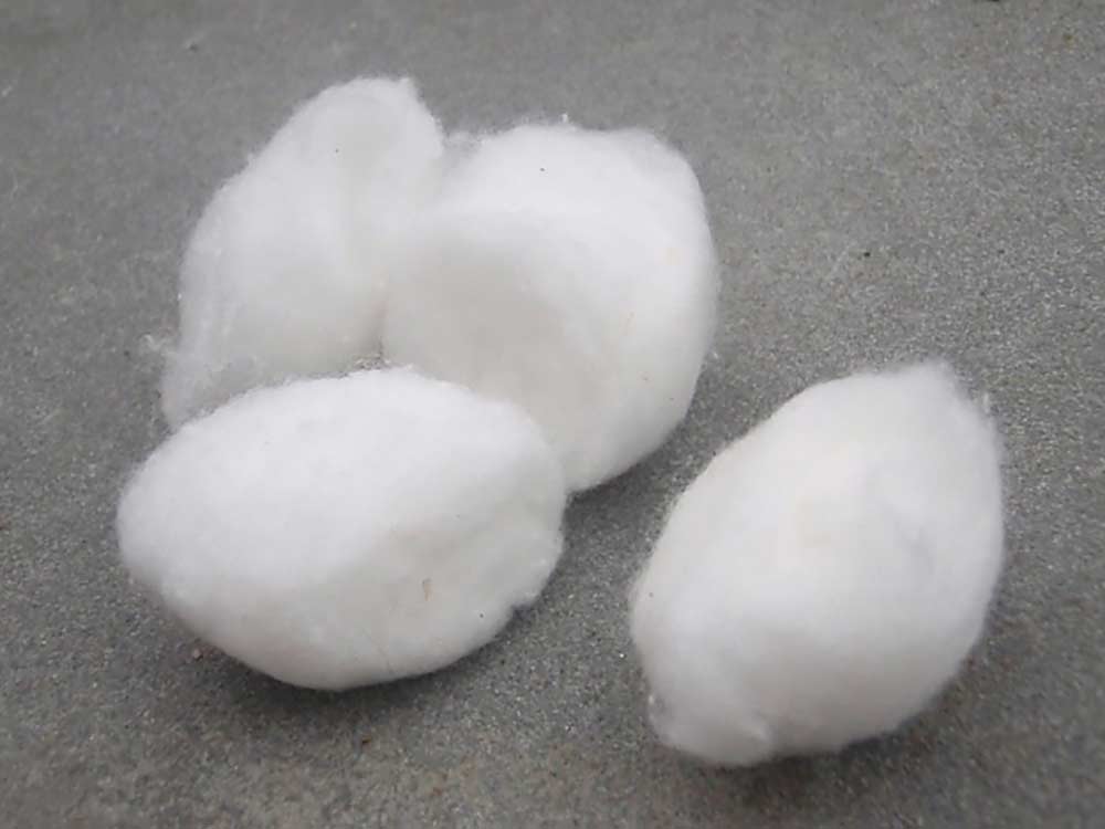 four cotton balls on a stone ground