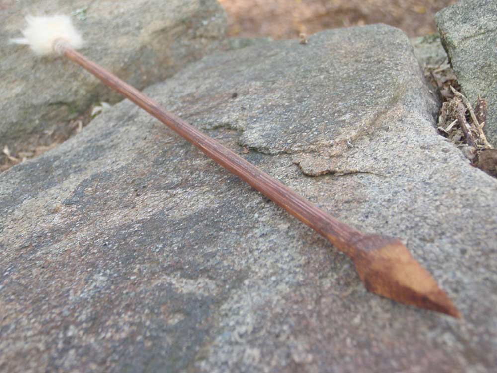 a wooden dart with cotton fletching