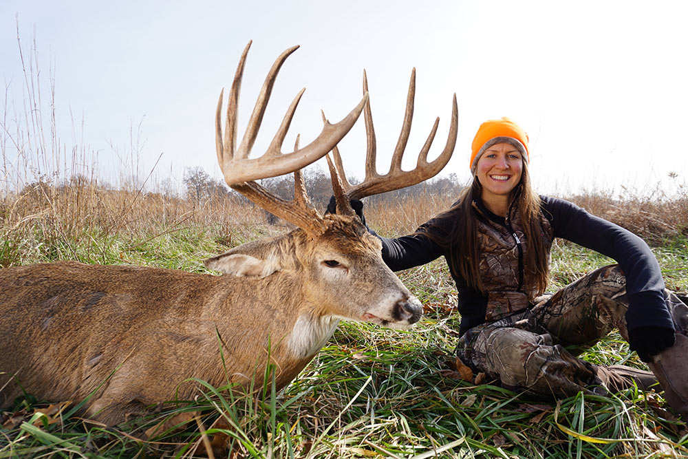 female hunter next to giant buck