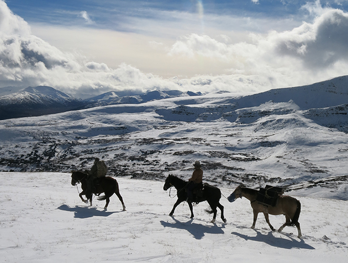 <em>High above rain clouds, the author's hunting party searches for mountain caribou on the snowy Spatsizi Plateau.</em>