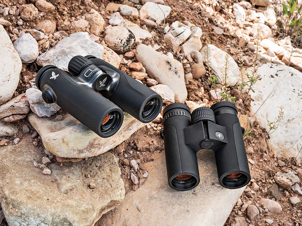 two pairs of binoculars sitting on rocks