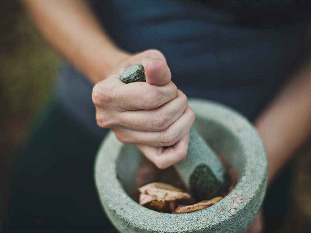person grinding herbs in a mortar and pestle