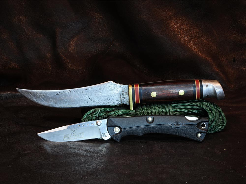 two hunting knives leaning on paracord