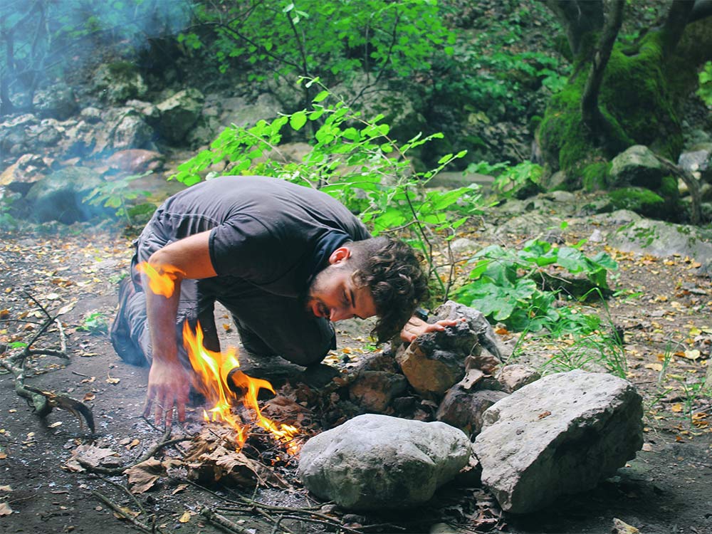 man lighting a fire in the outdoors