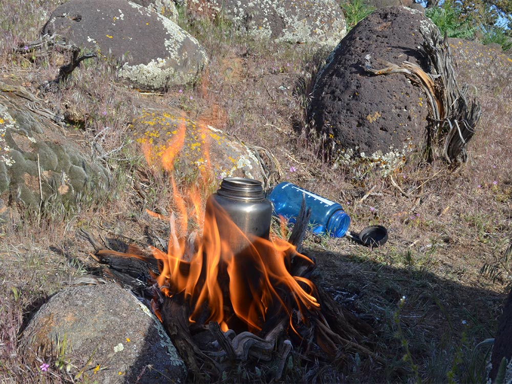 stainless steel canteen over a camp fire