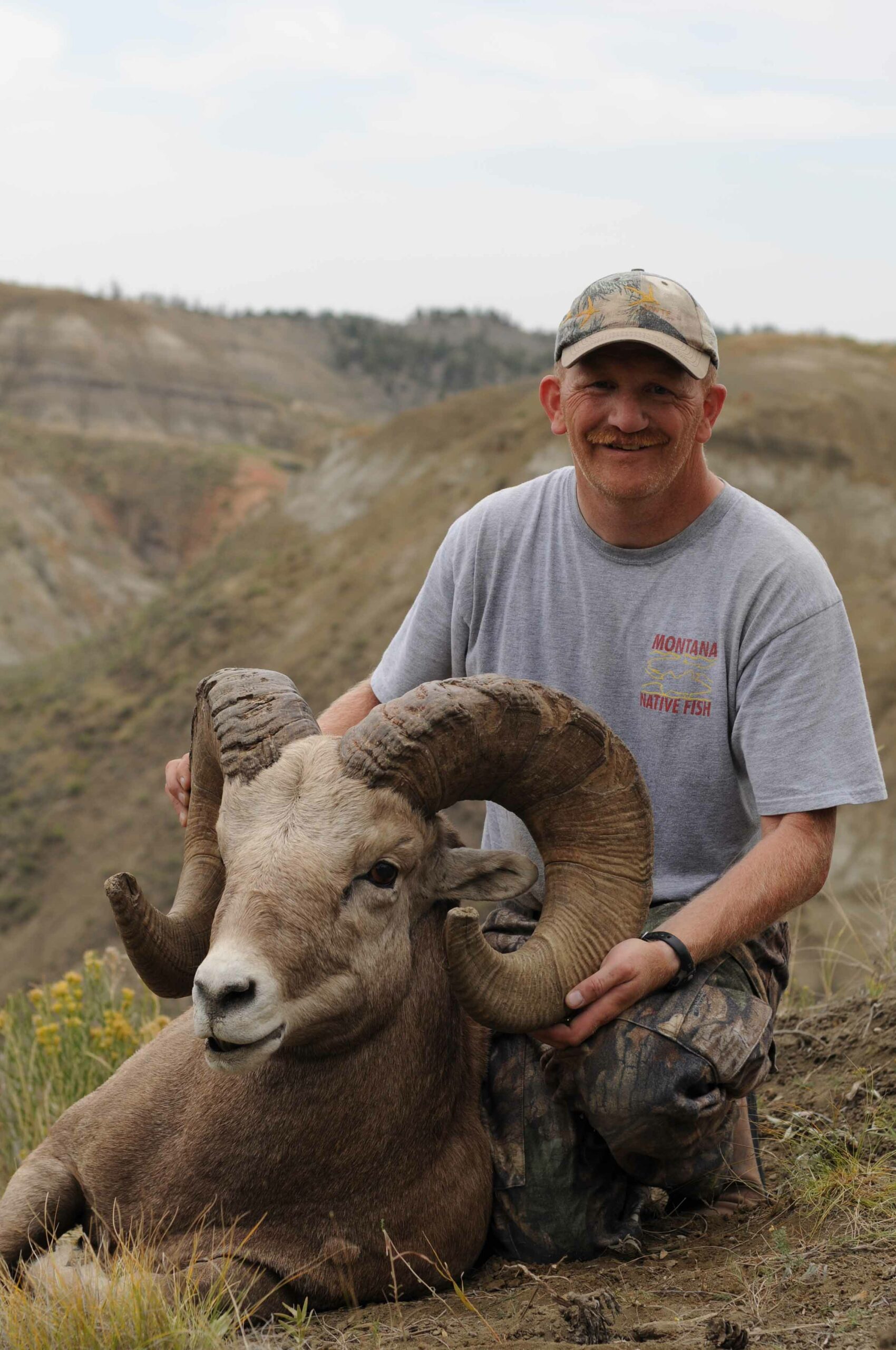 Mark poses with his trophy, the rough gumbo breaks behind him. He has taken a 9-1/2-year old ram on public land. The sheep will make the record book; we green score it at about 186 inches.