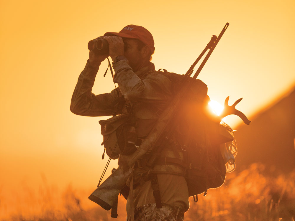 Hunter scoping a hunt with binoculars in the sunset