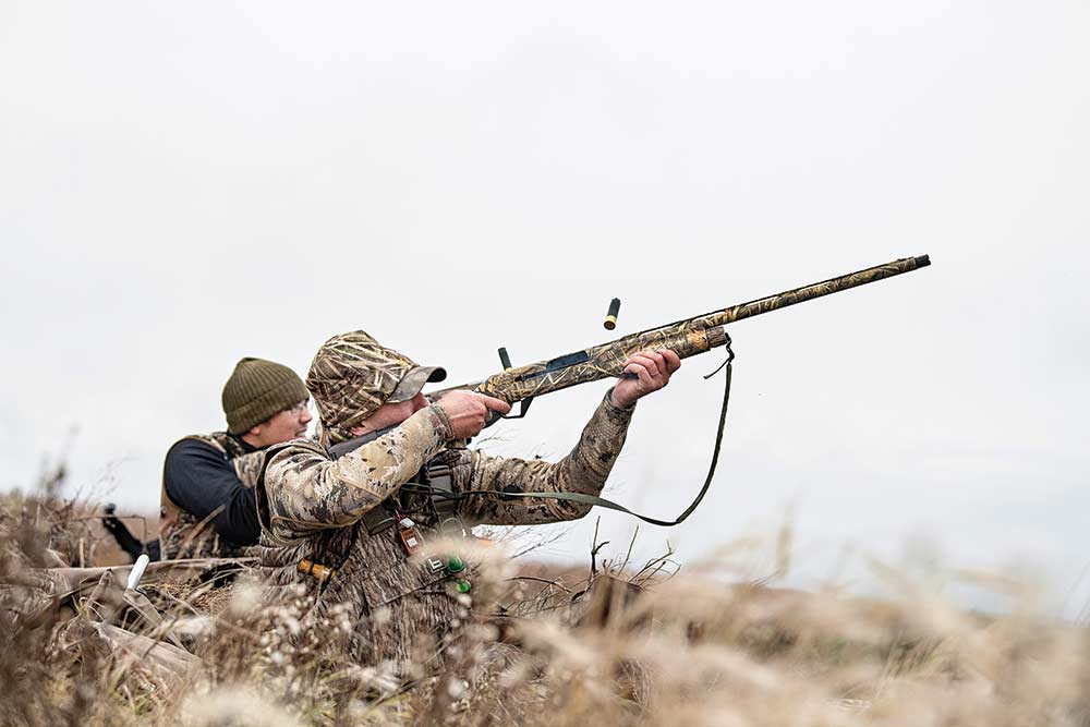 hunter aiming shotgun in field