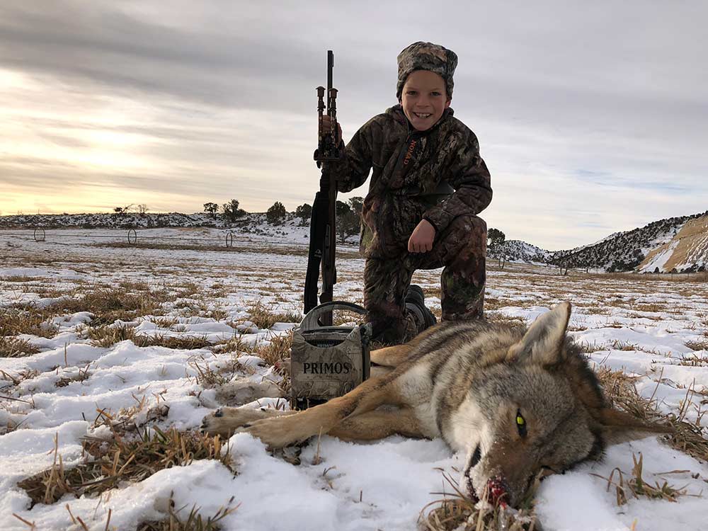 young boy kneeling next to coyote