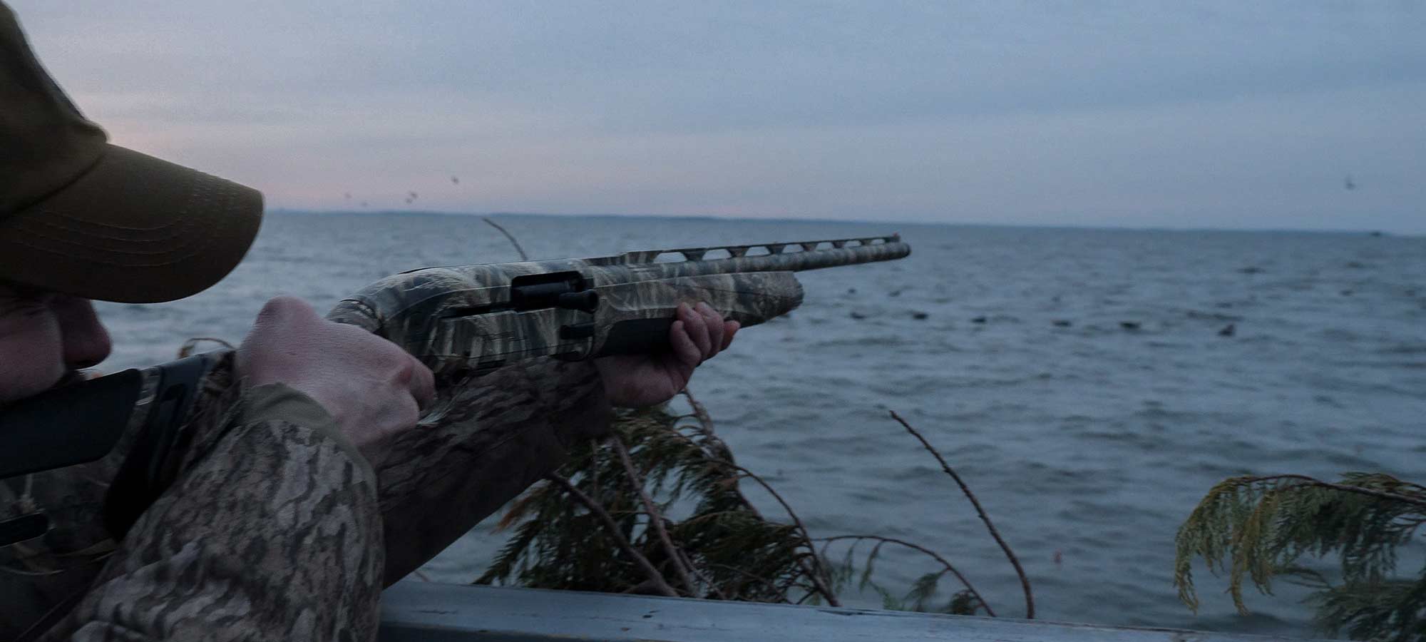 hunter aiming shotgun at sea ducks