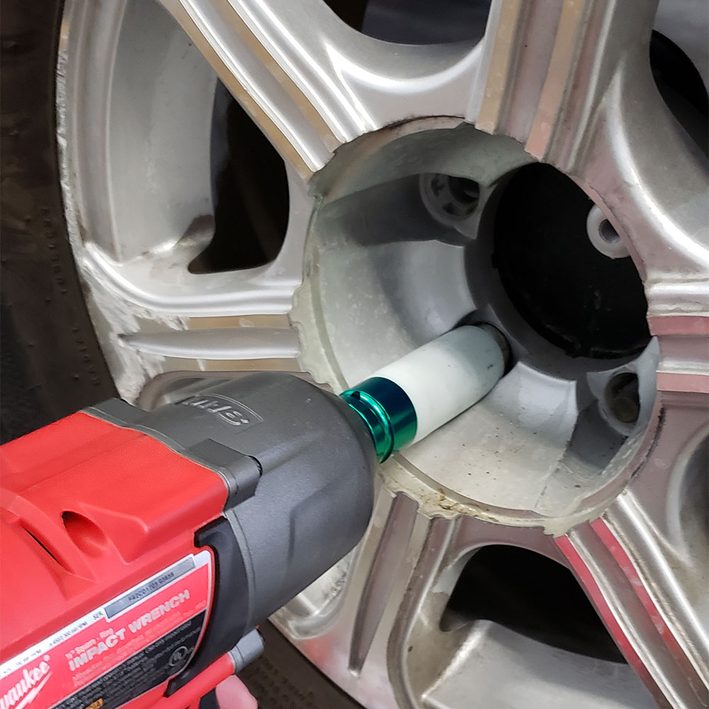 a red drill tightening the lug nuts on a tire