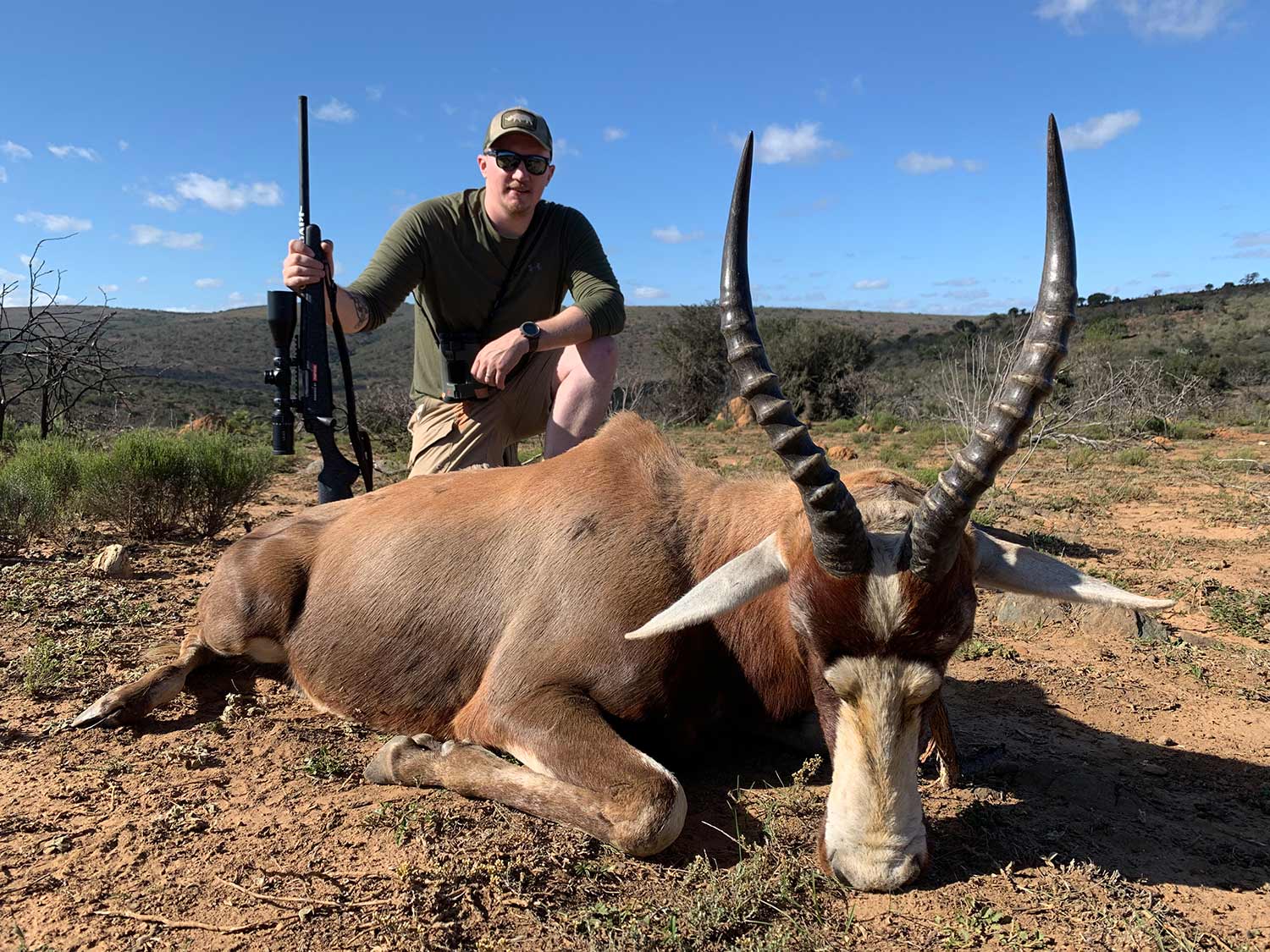 A hunter in africa next to a mature blesbok ram.