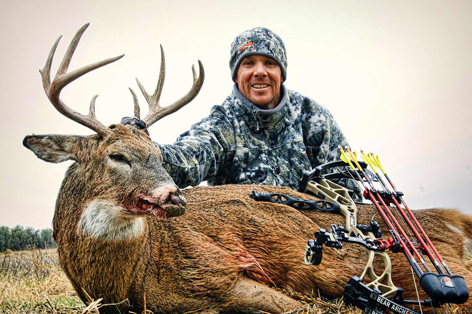 A hunter kneeling behind a Kansas buck.
