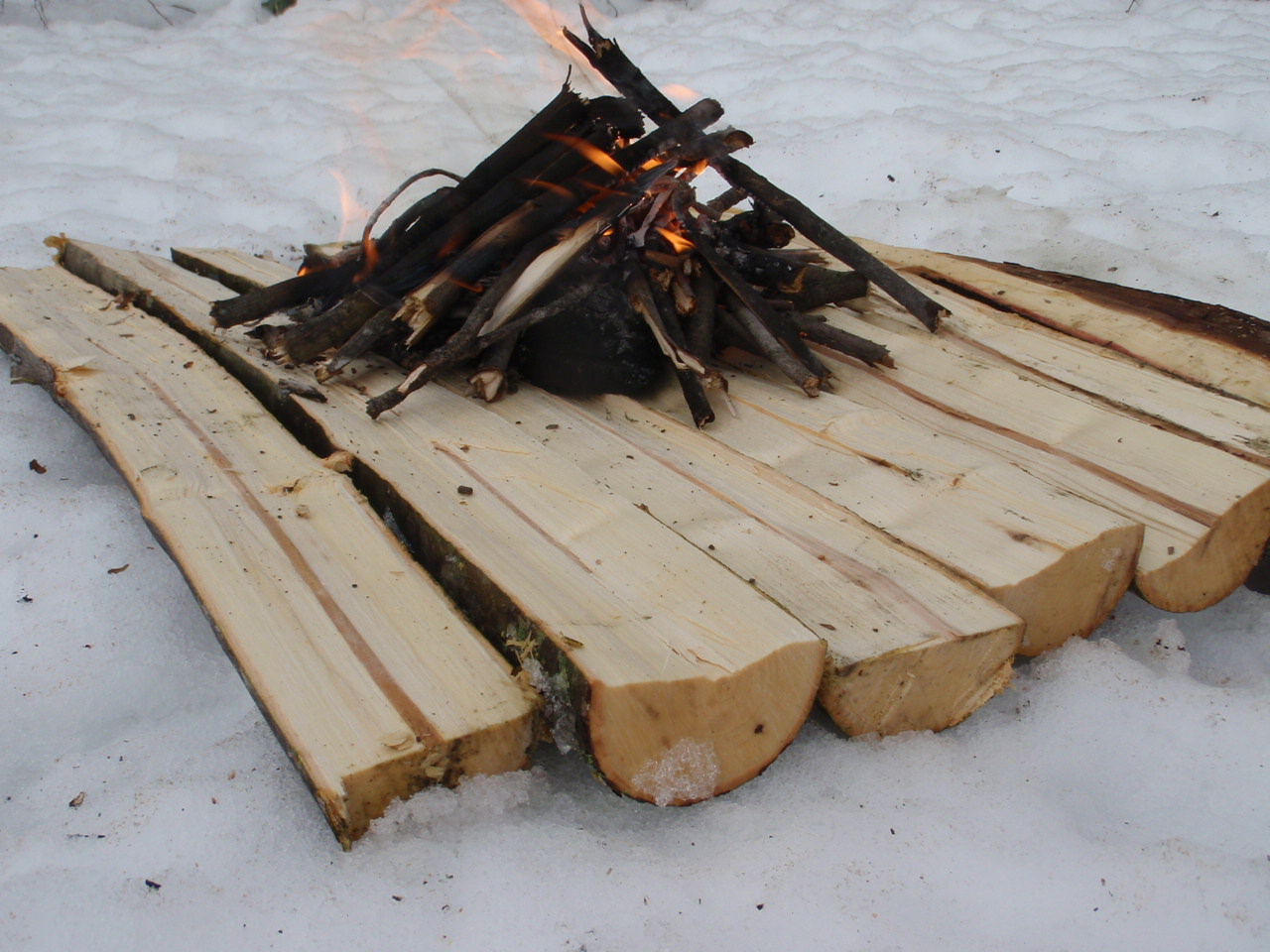 A fire built on planks of wood to keep dry from the snow.