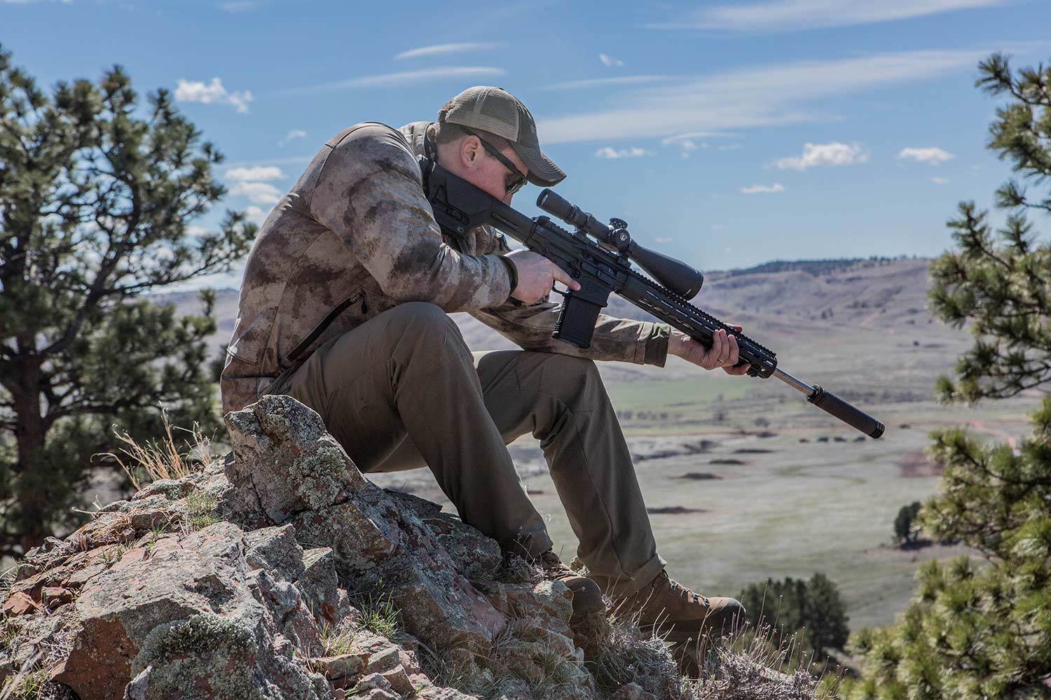 hunter firing a rifle with a muzzle suppressor.