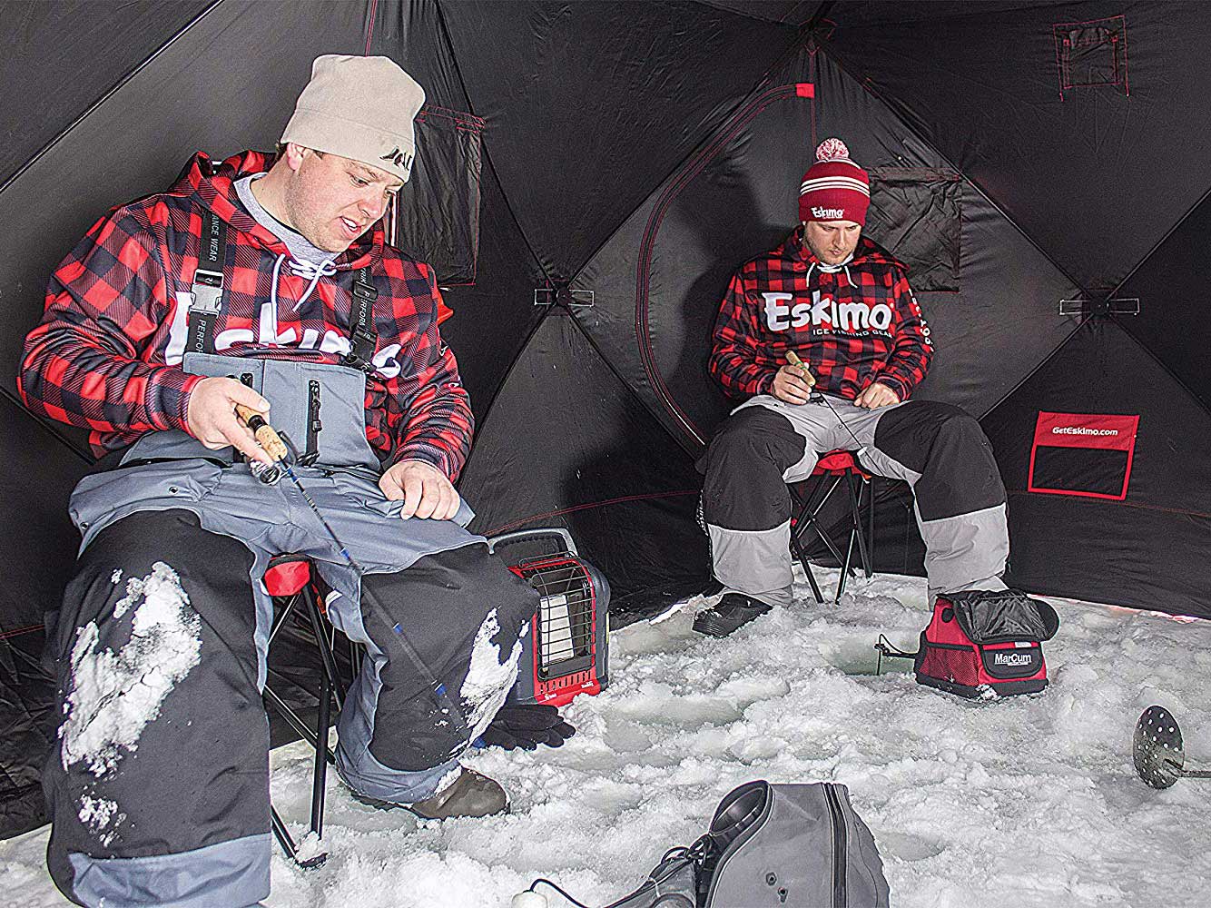 Fishermen sitting in ice fishing shelter.