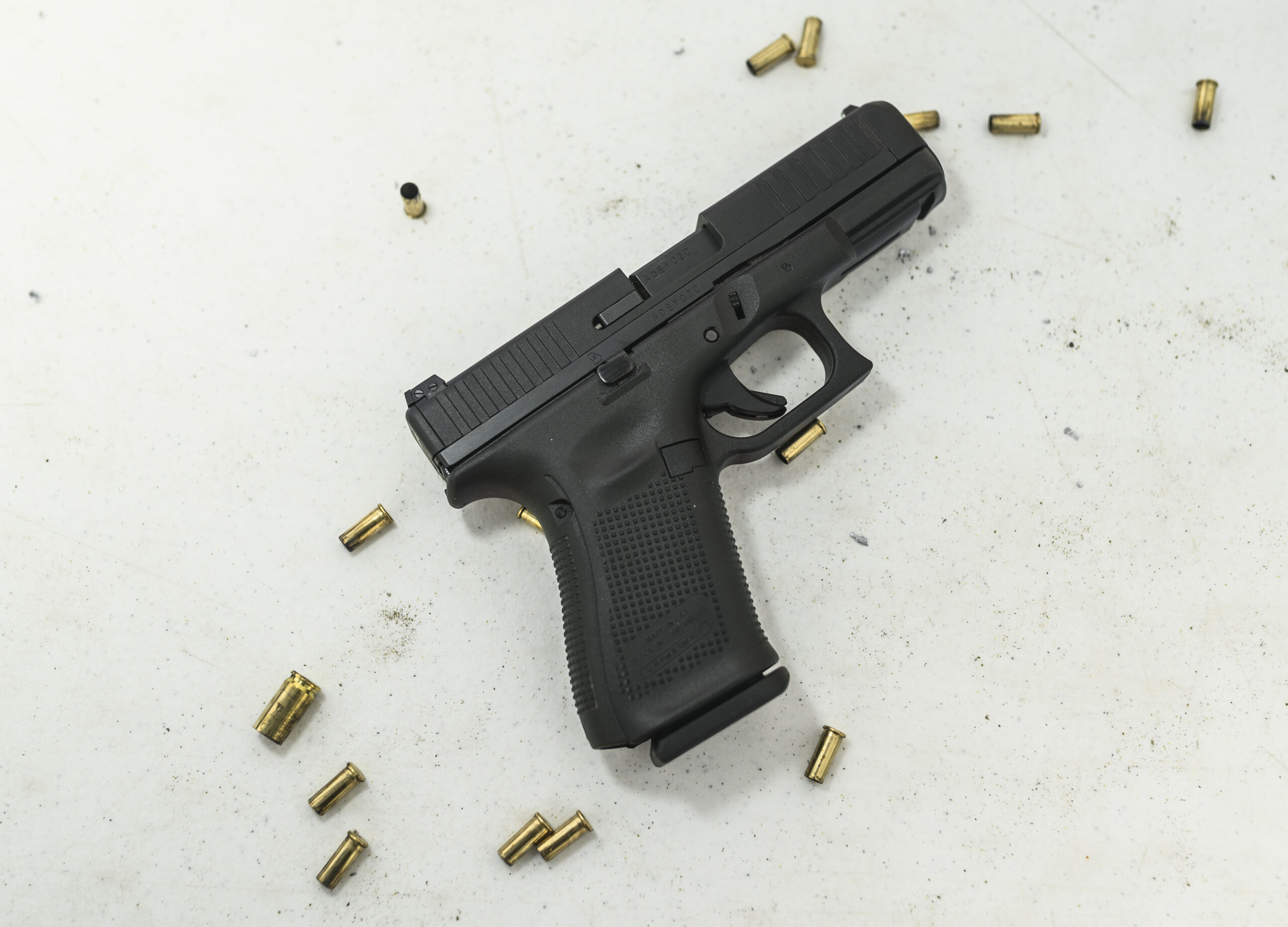 Glock G44 handgun on a white background with empty rimfire cartridge cases scattered around it