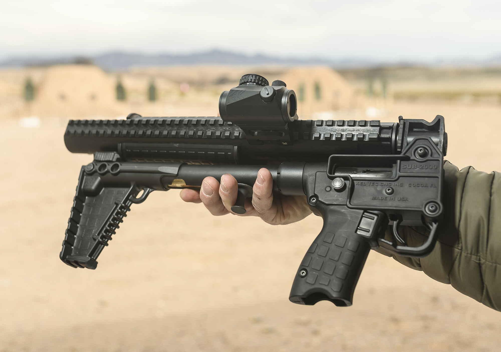 a 9mm pistol-caliber carbine, folded in half, in hand at the range