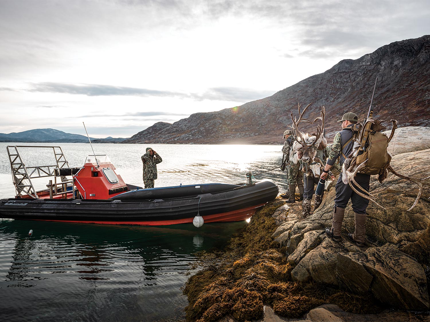Caribou hunters next to a hunting guide boat.