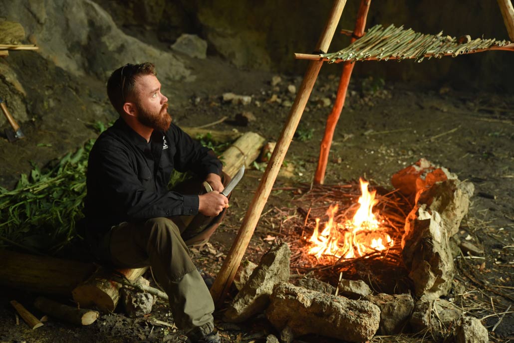 Man by a survivalist campfire.