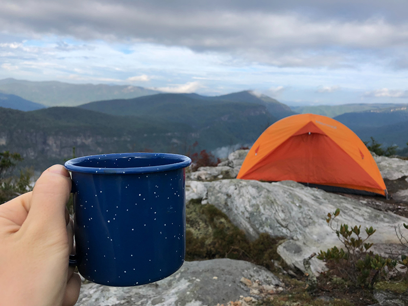 holding outdoor mug and tent.