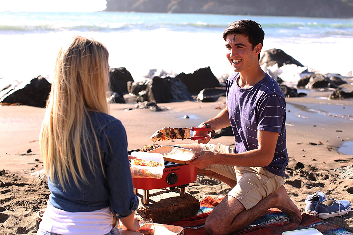 two people grilling on a beach