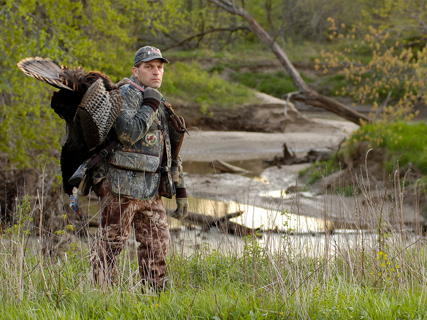 Hunter with a turkey near a river bottom.