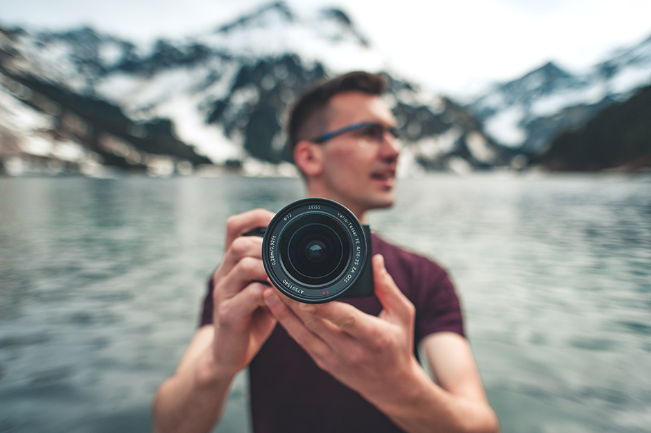 person with a camera in front of a lake
