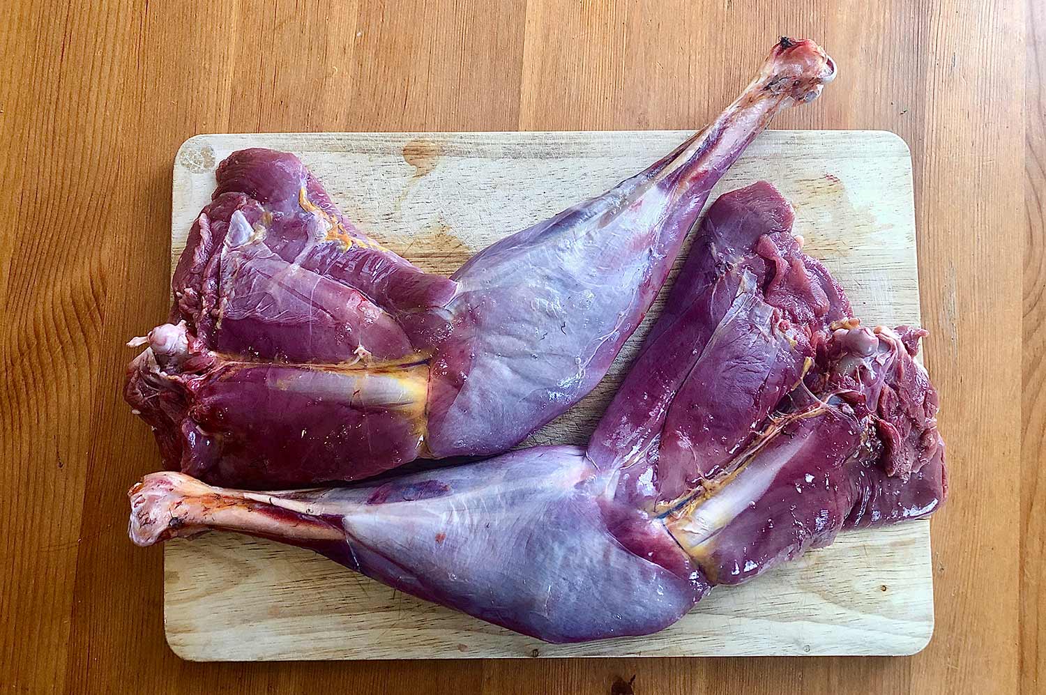 Two turkey legs and thighs on a cutting board.