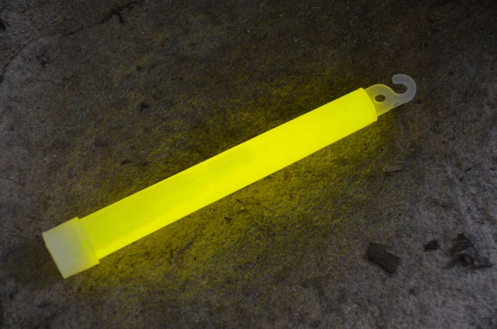 A yellow glowstick on the ground at night.