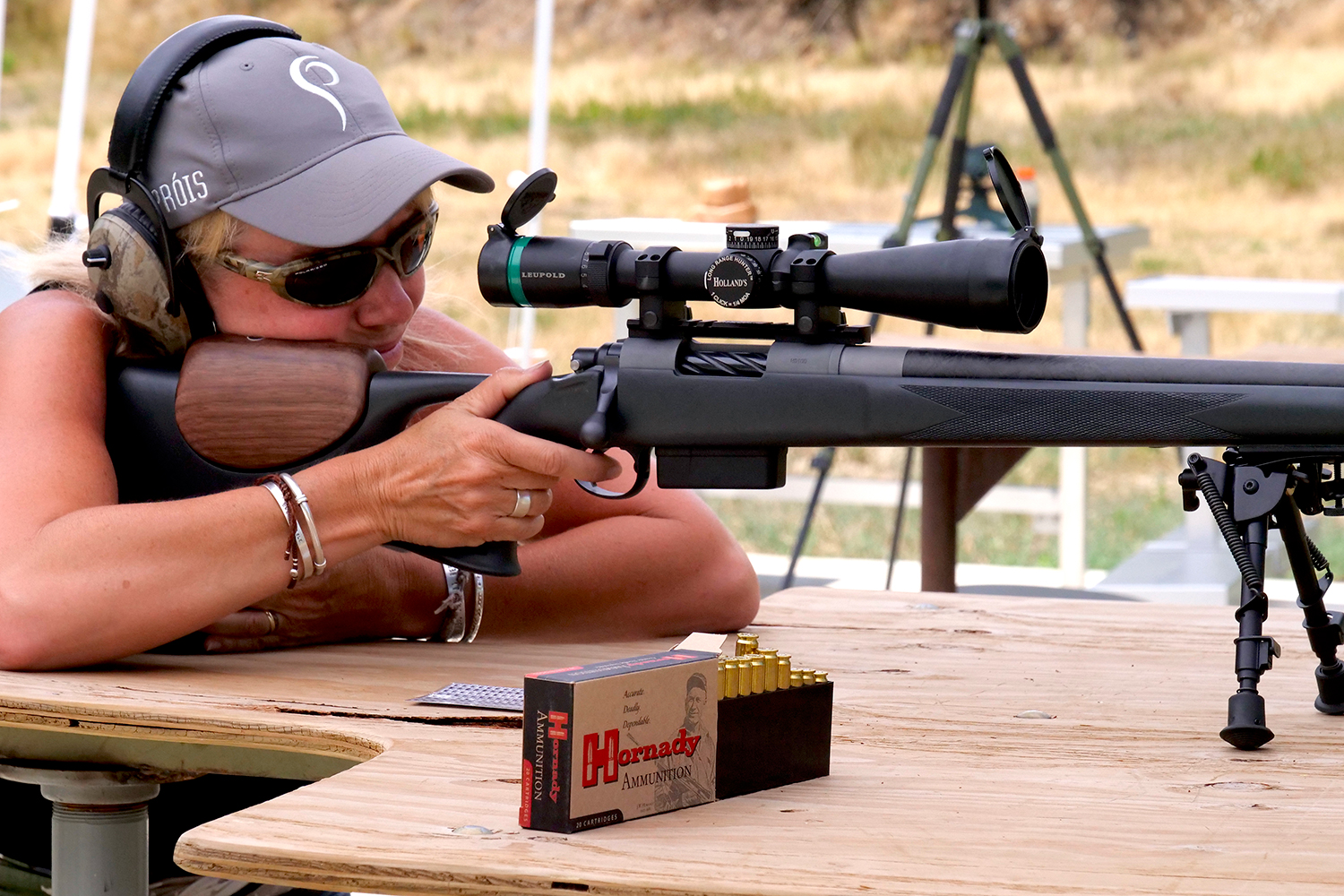A woman rifle shooter aims a rifle at a shooting range.