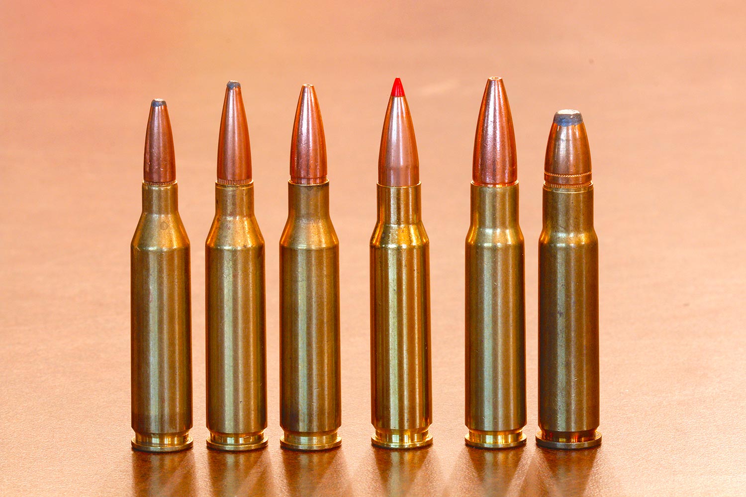 A lineup of rifle cartridges on a table.