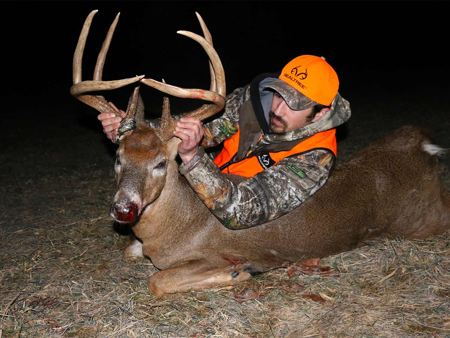 A hunter in camo with a large 8-point whitetail buck.