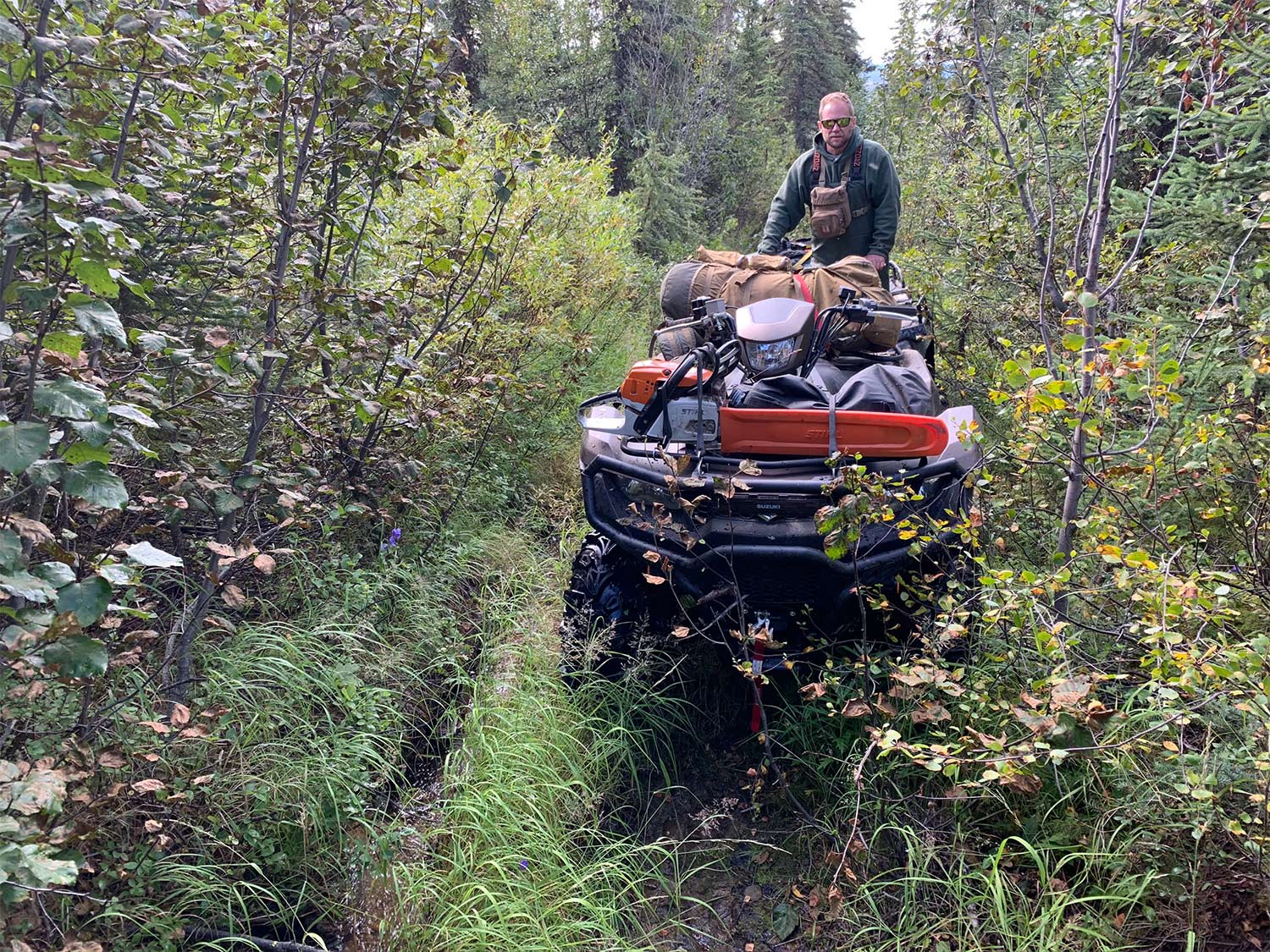 A man on a four-wheeler equiped with brush bumpers.