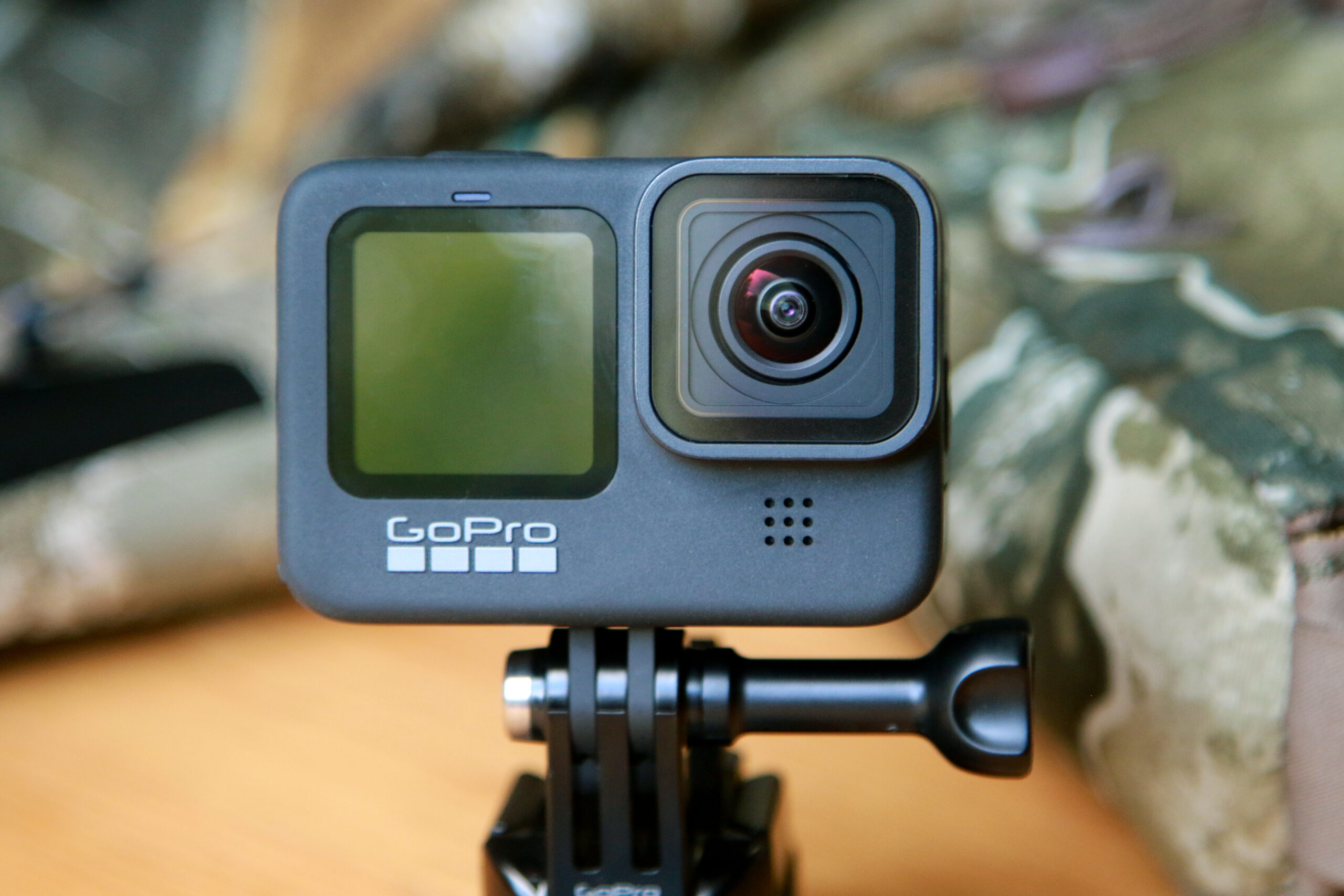 black gopro hero9 action camera with front lens and camo in the background