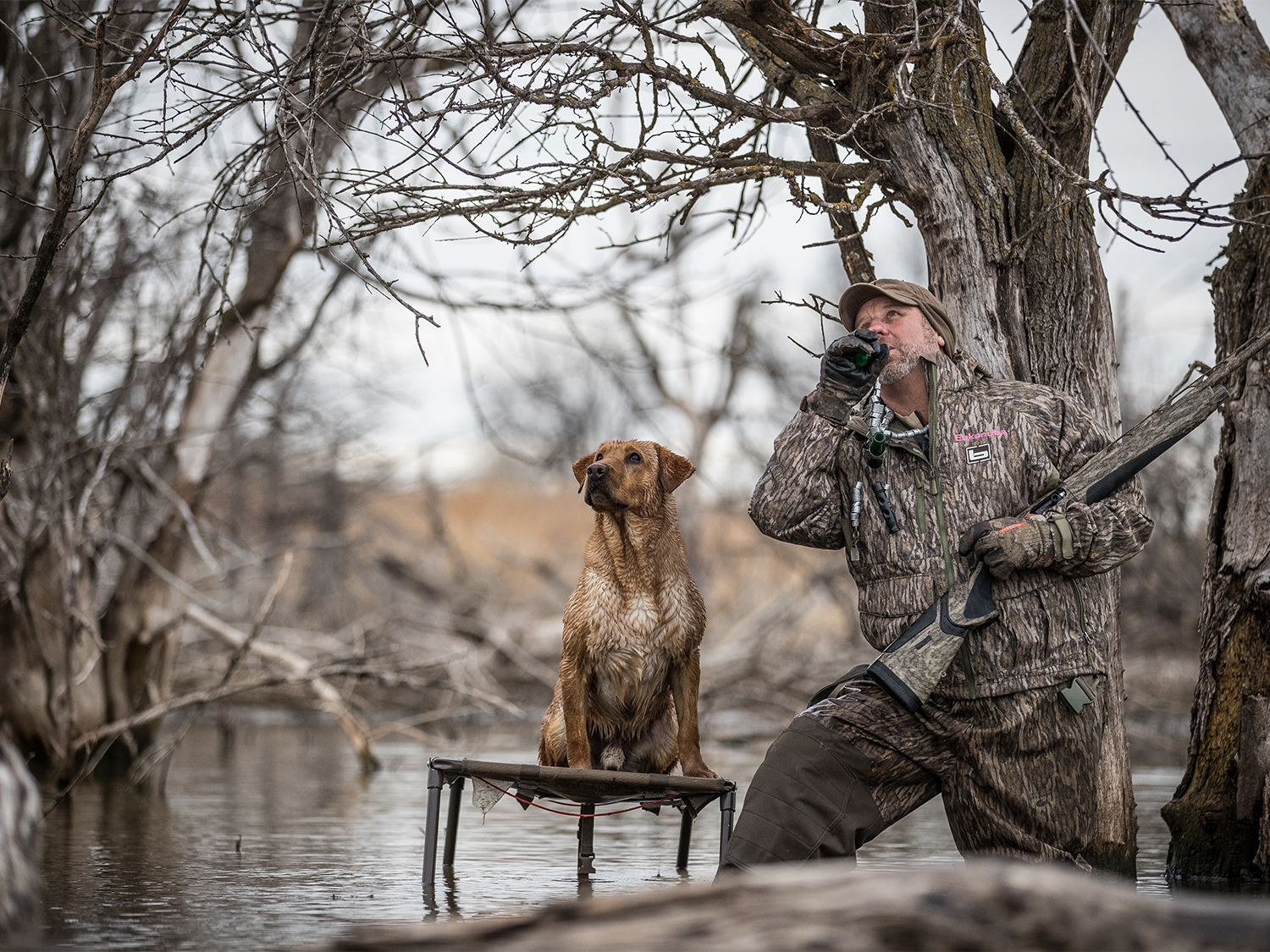 A hunter wading in the water on a duck call.