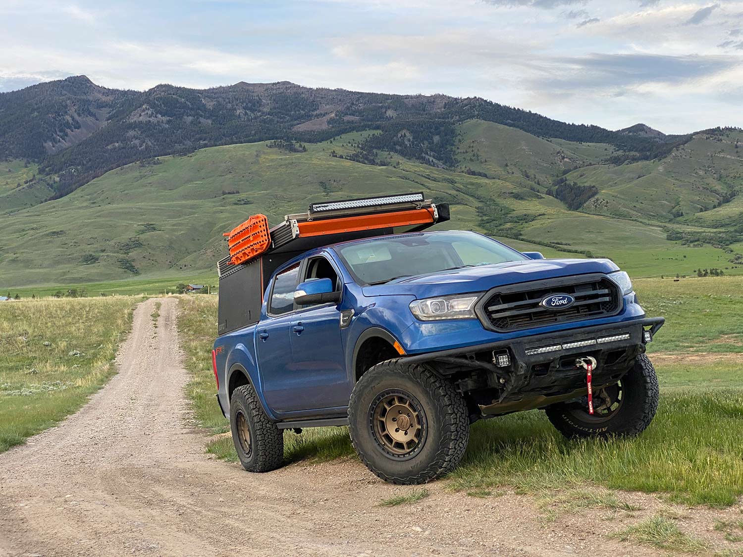 A blue ford pickup truck outfitted with custom attachments and gear.
