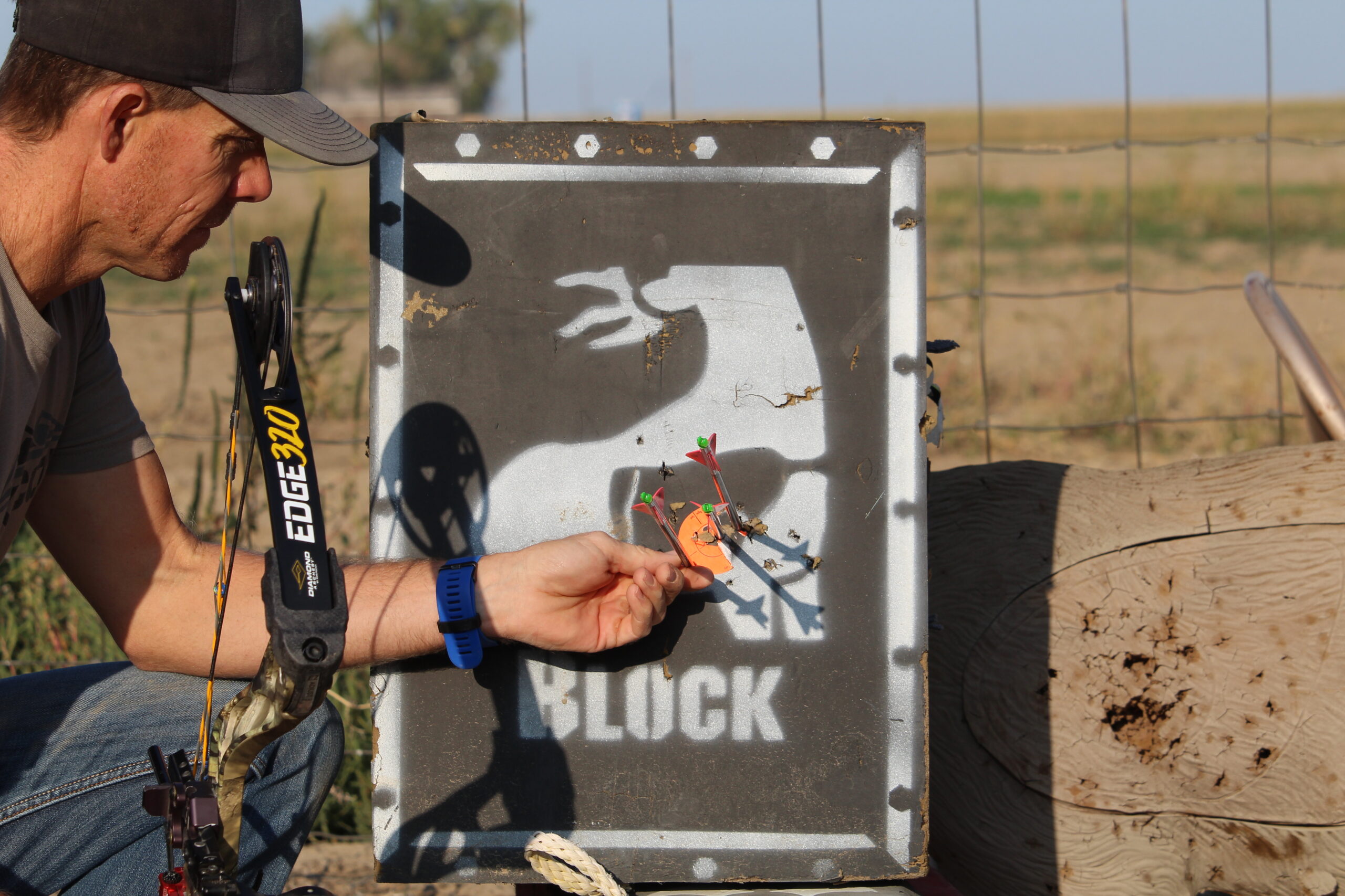 An archer examines arrow groups in a block target while holding a Diamond Edge 320 bow.