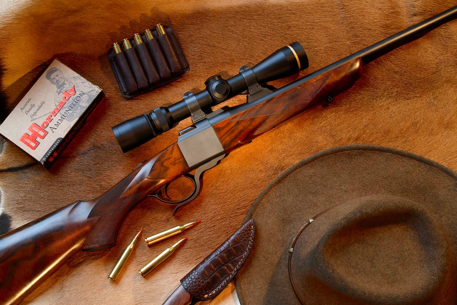 A hunting rifle and western hunting gear on a deer skin.