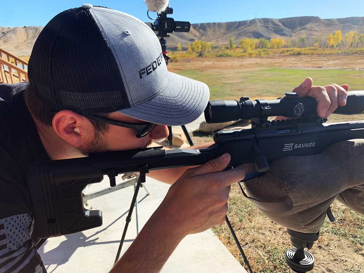 A man aims a rimfire rifle on a shooting range.