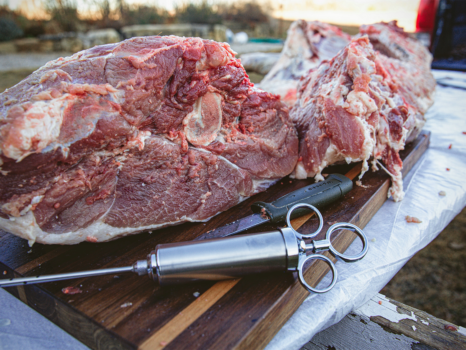 Slabs of wild game meat and a flavor syringe injector.