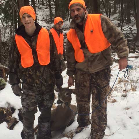 Two hunters drag a dropped deer through the snow