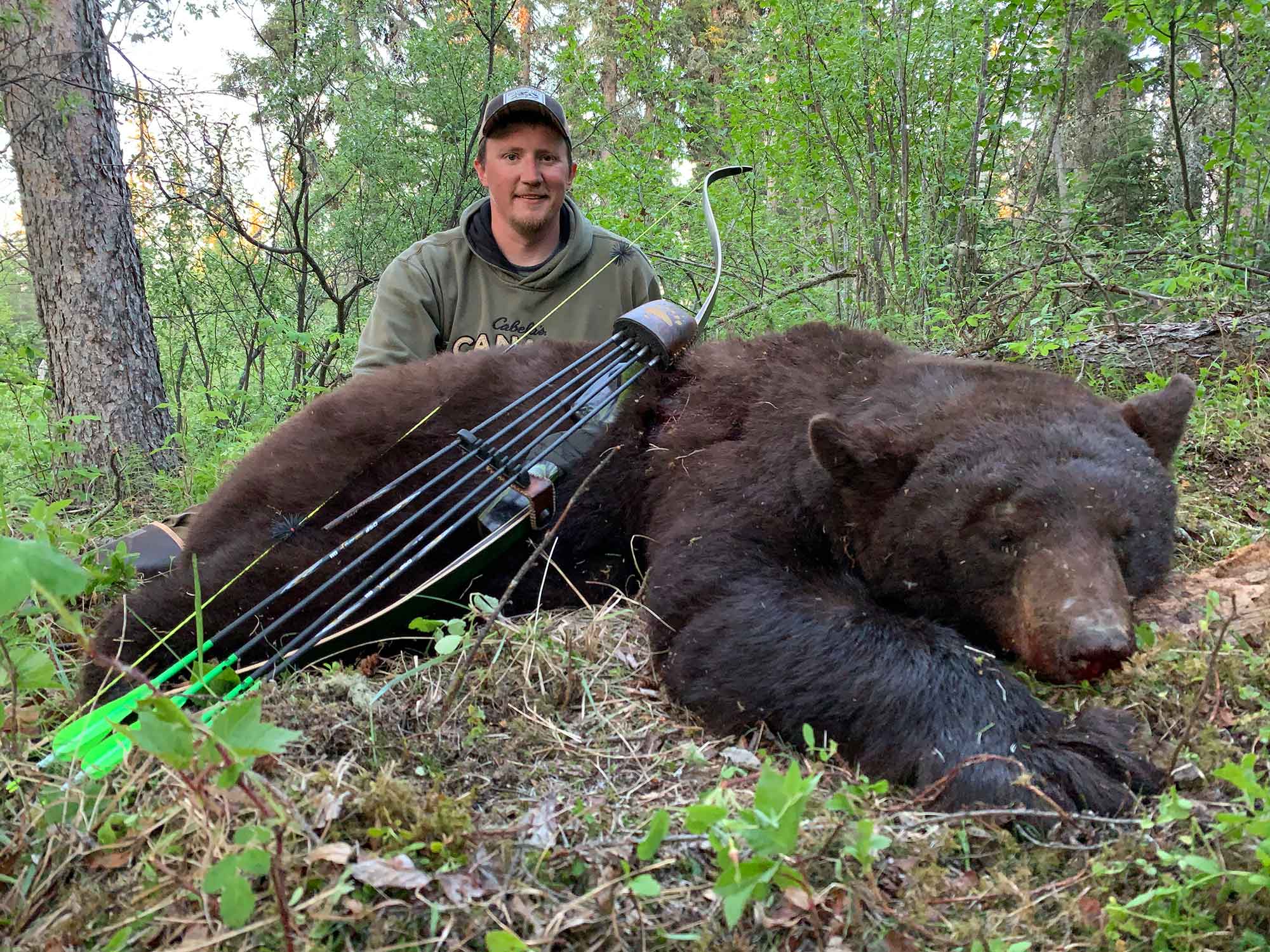 Hunter beside dead bear and bow