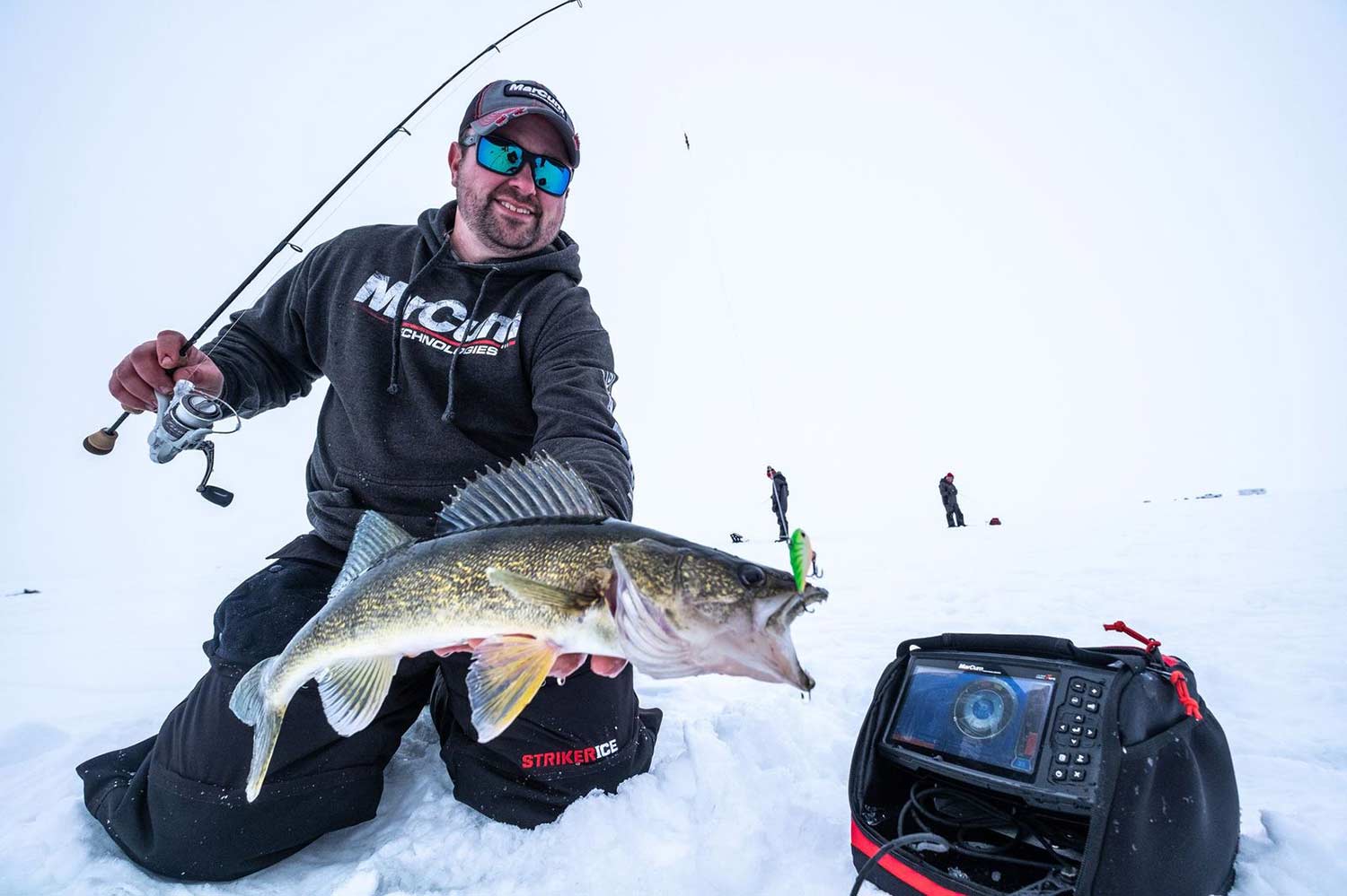 An angler holds a walleye caught from an ice fishing hole.