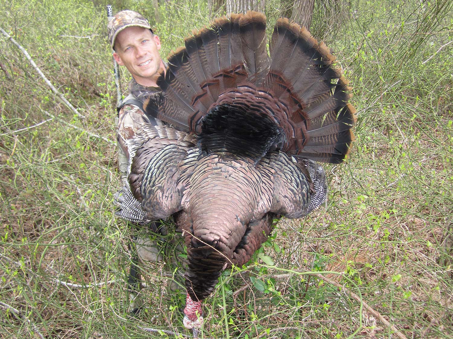 A hunter holds up a large turkey.