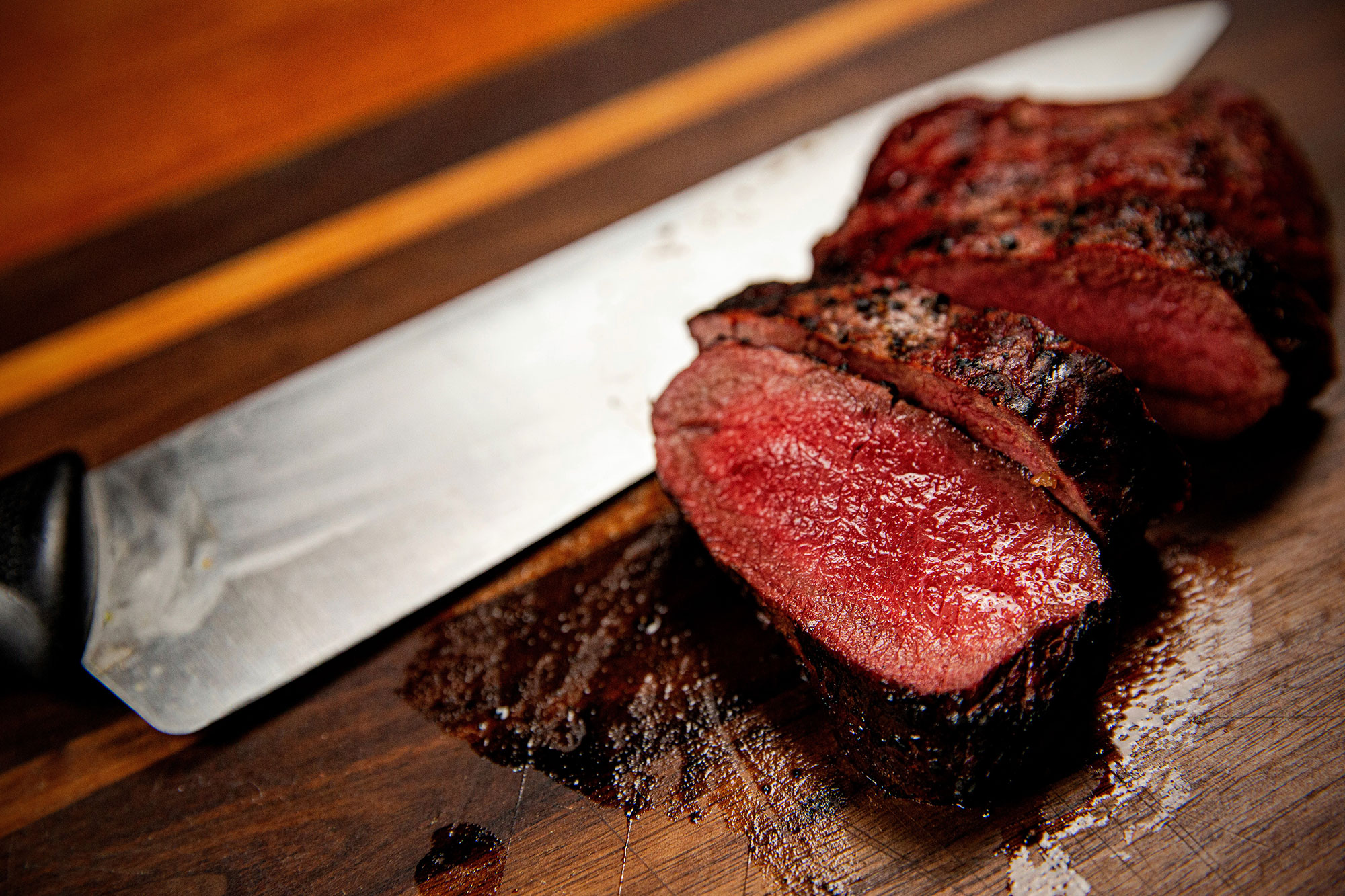 A perfectly cooked medium-rare venison steak on a cutting board.