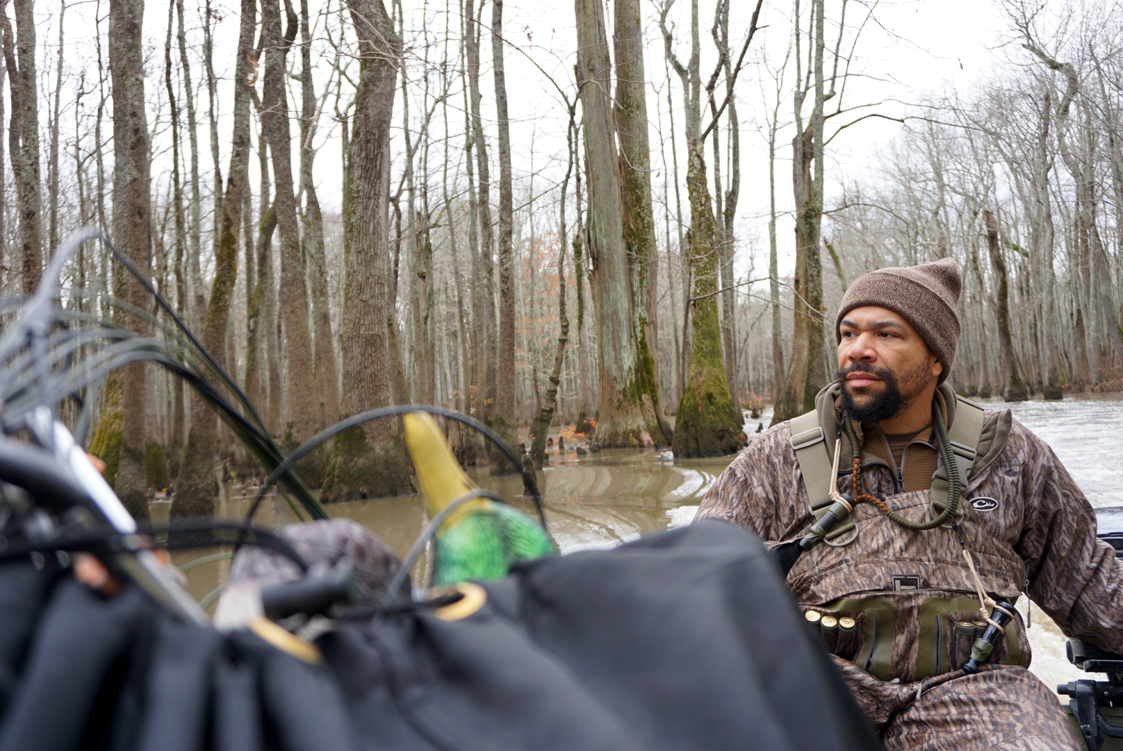 A duck hunter steers a boat loaded with decoys through flooded timber.