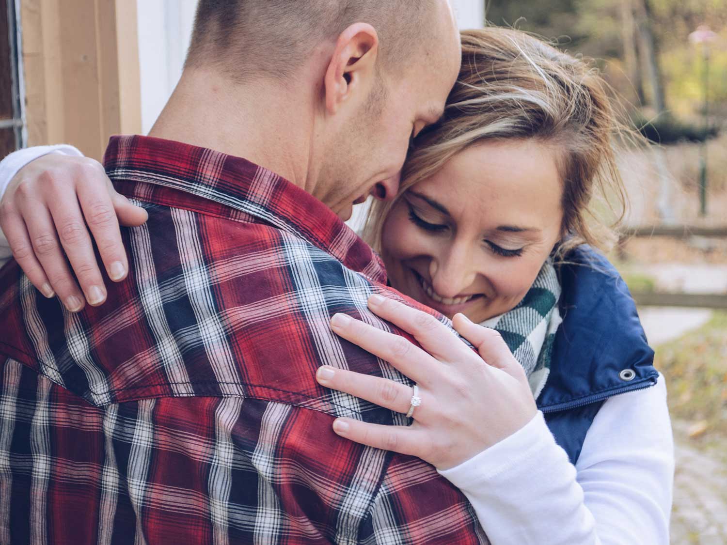 Woman hugging man wearing flannel shirt.