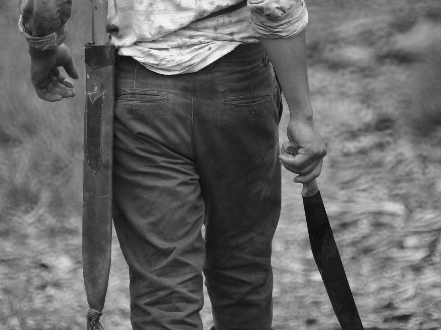 A black and white image of a man holding the best machete.